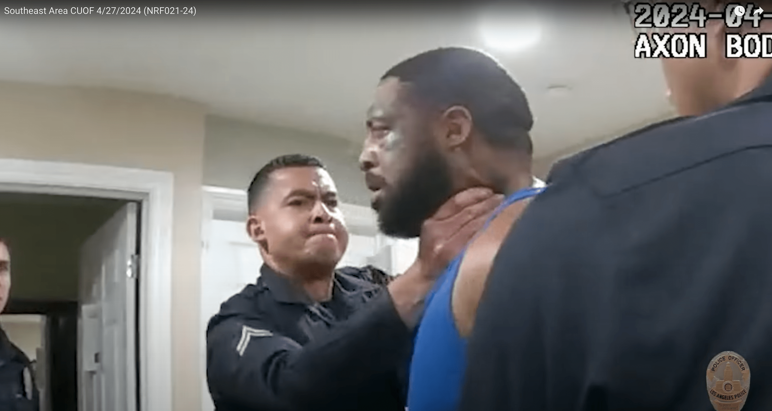 An unidentified Los Angeles police officer grabs Dominque Langlois by the neck. Langlois is handcuffed.